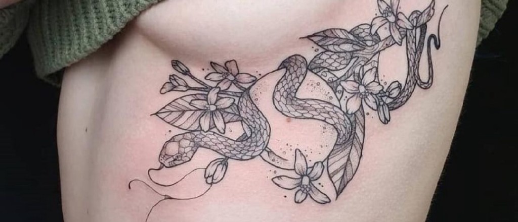 Fine-line snake and flower tattoo on the ribs, one of the most painful spots